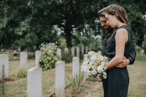 Couple standing together by a gravestone