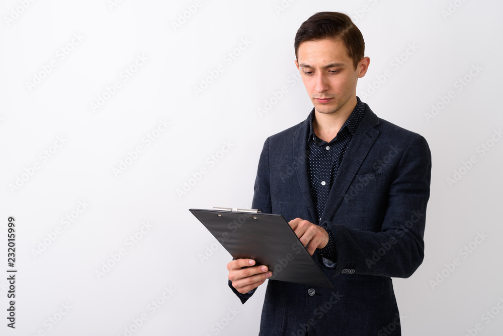 Studio shot of young handsome businessman reading on clipboard a Studio shot of young handsome businessman reading on clipboard a