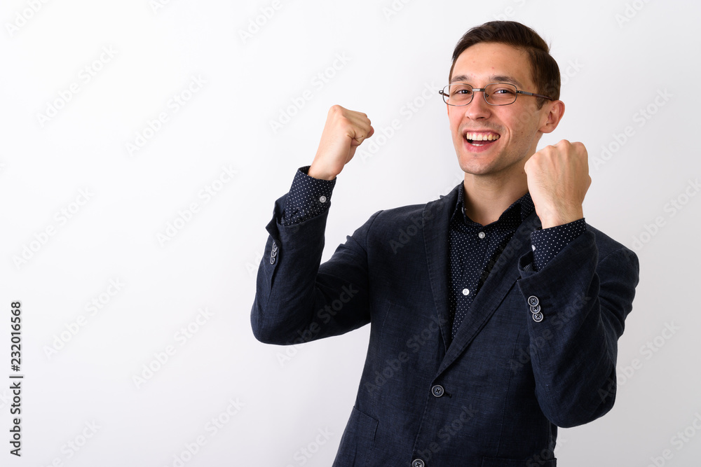 Studio shot of young happy businessman smiling and looking excit Studio shot of young happy businessman smiling and looking excit