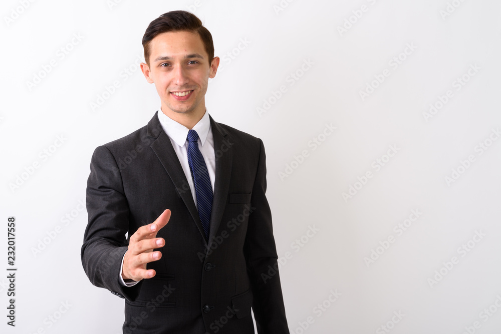 Studio shot of young happy businessman smiling while giving hand Studio shot of young happy businessman smiling while giving hand