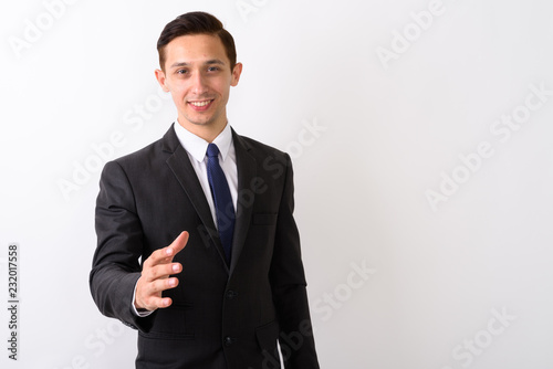 Studio shot of young happy businessman smiling while giving hand
