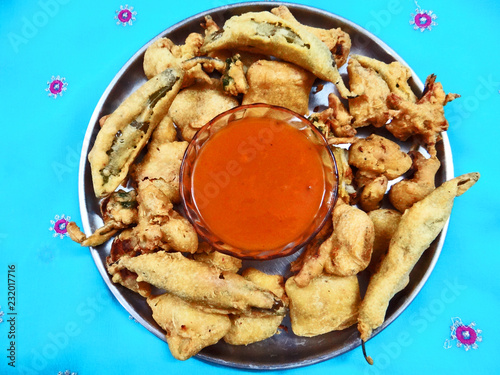 A plate of different kind of Fresh Pakorey with red sauce, A fried snack prepared from Chickpea flour and seasonal vegetables. photo