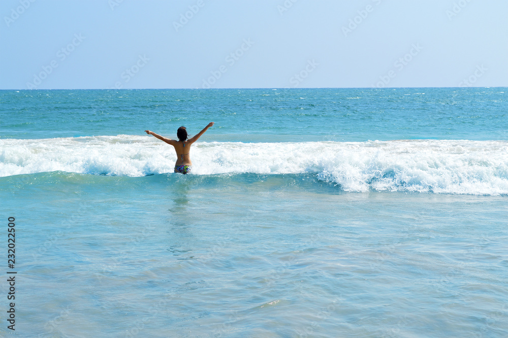 happy girl enjoys the waves of the Indian ocean on the island of Ceylon