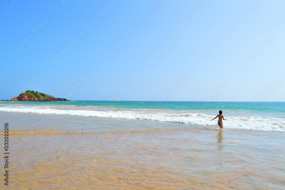 happy girl enjoys the waves of the Indian ocean on the island of Ceylon