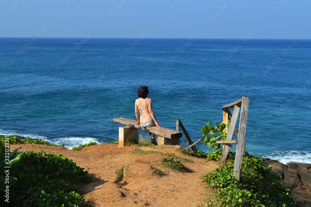 the girl looks at the Indian ocean on the beach of the island of Ceylon