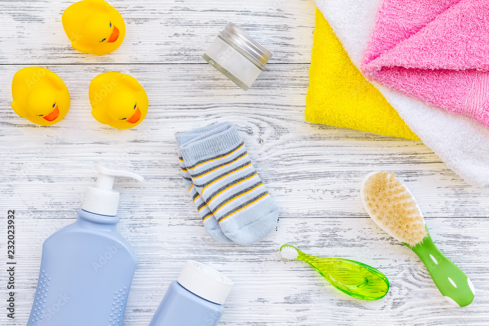 Shower accessories for child. Set with shampoo, towel, soap, gel, towel, brush and yellow rubber duck on grey wooden background top view pattern Shower accessories for child. Set with shampoo, towel, soap, gel, towel, brush and yellow rubber duck on grey wooden background top view pattern