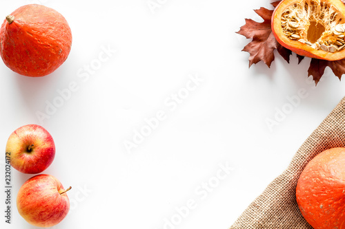 Composition with autumn vegetables and leaves in red and orange colors. Brown dried leaves, pumpkin, apple on white background top view space for text