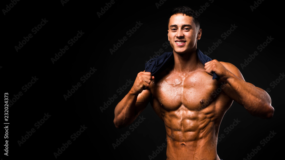 Portrait of handsome muscular guy with towel in the neck posing over a dark background.