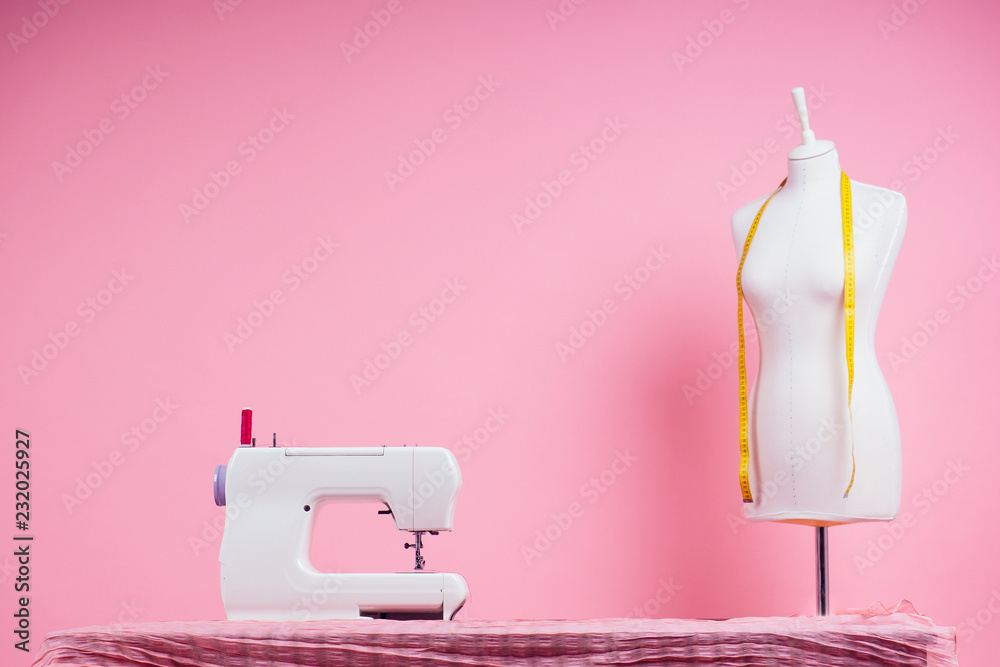 sewing pattern,sewing machine and maniken in studio pink background.seamstress curve template. tailor creates a collection outfits sews clothes in workshop. young woman designer clothes notes ideas