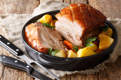 German recipe crispy pork served with vegetables and gravy close-up in a pan on the table. horizontal