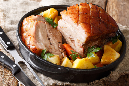 Traditional Bavarian crispy pork Krustenbraten baked in beer with vegetables close-up in a pan on the table. horizontal