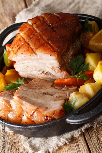 Krustenbraten Pork Roast with Crispy Rind with vegetables close-up in a frying pan. Vertical