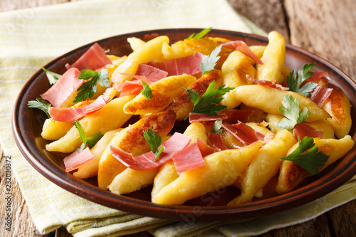 Recipe for German potato noodles called Schupfnudeln, served with bacon and parsley close-up on a plate. Horizontal photo