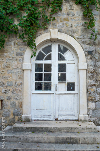 Old, glass, paneled white wooden door in the old building.