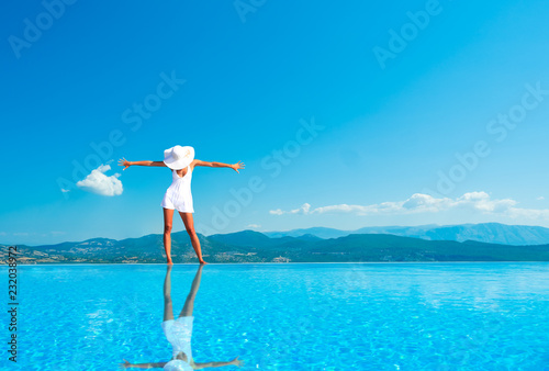 Woman enjoying relaxation in pool and looking at the view in Santorini