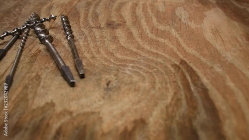 Old drillbits on wooden table in woodshop. Nice panning over drillbits. Very nice littlebit warm light. photo