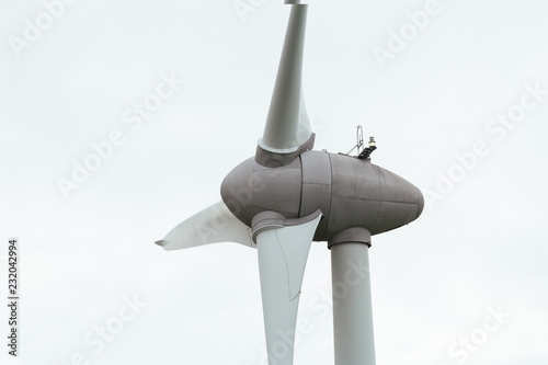 Spinning wind turbine on a cloudy day. Modern technology of electrical power generation. Renewable energy sources concept. Ecology and environmentally friendly energy production. Close up