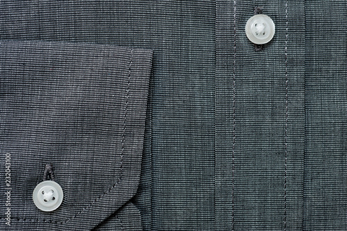 Texture of dark gray shirt fabric with white buttons close-up shot