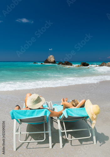 Couple on sunbeds relaxing at the beach in Lefkada