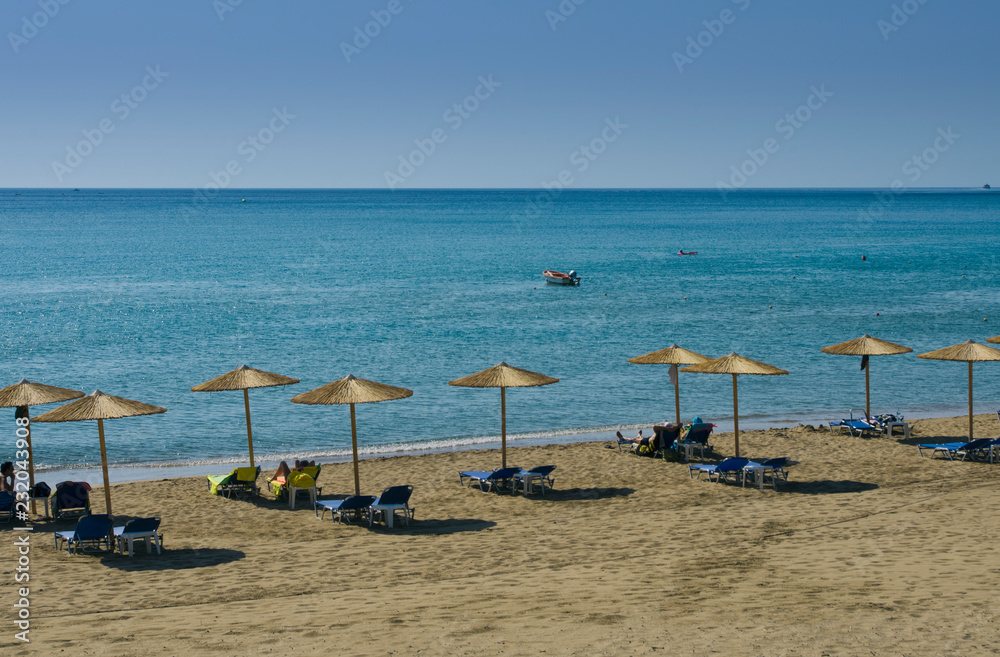Mediterranean landscape with beach umbrellas and sunbeds in the background blue sky Mediterranean landscape with beach umbrellas and sunbeds in the background blue sky