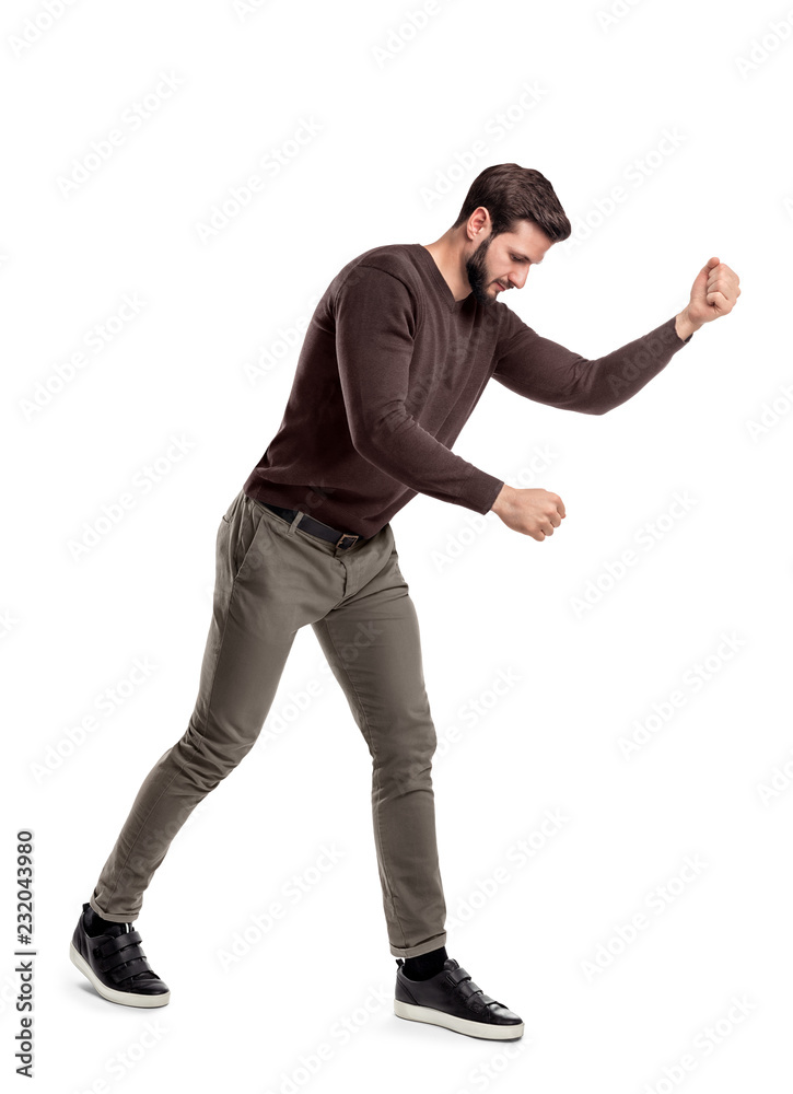 A fit bearded young man in casual clothes tries to hit or make something as if holding an invisible tool.