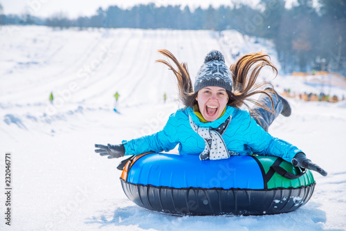 young smiling girl ride sleigh snow tubing hill winter activity photo
