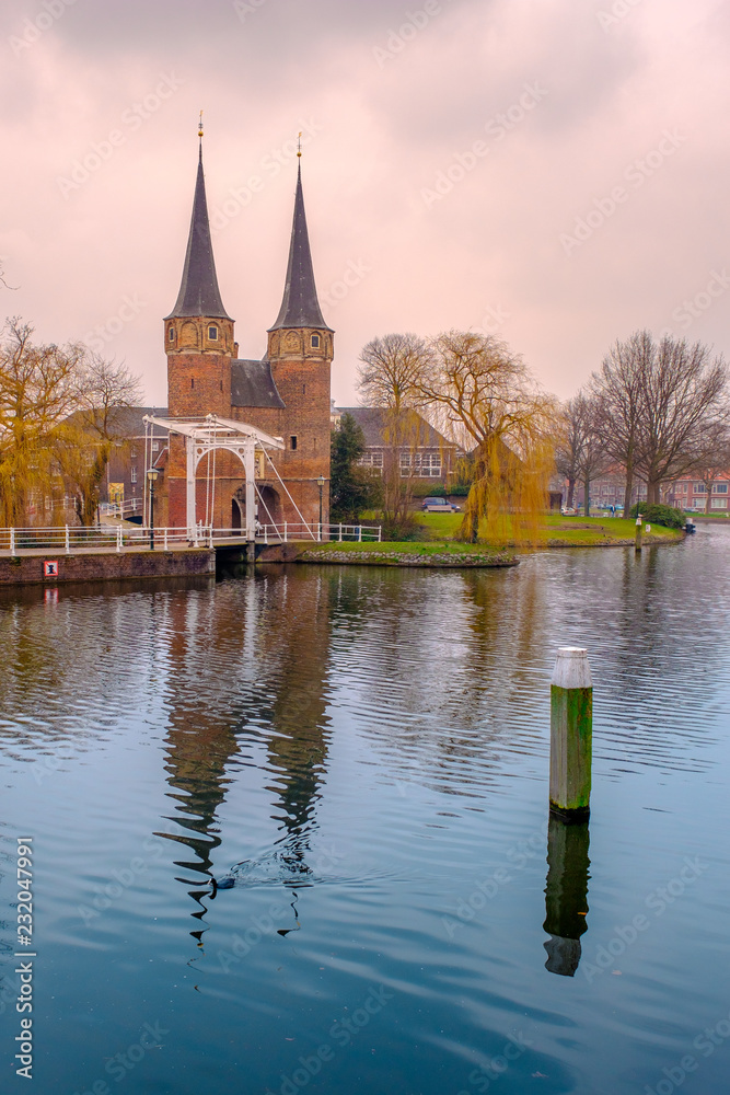 Evening view of the canal and the VVE Oostpoort de Delft. Dutch city in the spring after sunset. Holland, Netherlands. Evening view of the canal and the VVE Oostpoort de Delft. Dutch city in the spring after sunset. Holland, Netherlands.