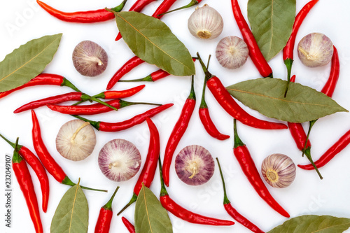 Spicy red chilli peppers, bay leaves and garlic on white background.