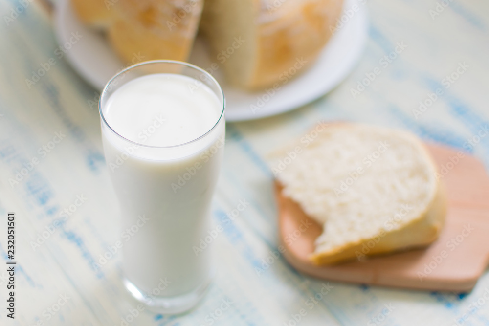A glass of milk and white bread on a wooden background. A glass of milk and white bread on a wooden background.