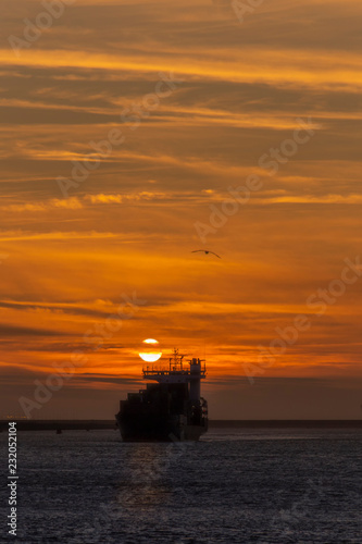 Container vessel leaving the Rotterdam seaport toward the deep ocean under a vivid sunset, Amsterdam, Netherlands © Ankor light
