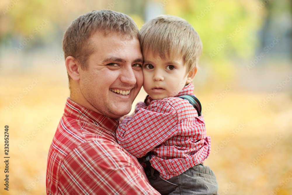 Father and son are playing and having fun in autumn city park. They posing, smiling, playing. Bright yellow trees. Father and son are playing and having fun in autumn city park. They posing, smiling, playing. Bright yellow trees.
