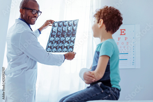 Positive friendly doctor looking at his patients xray image photo