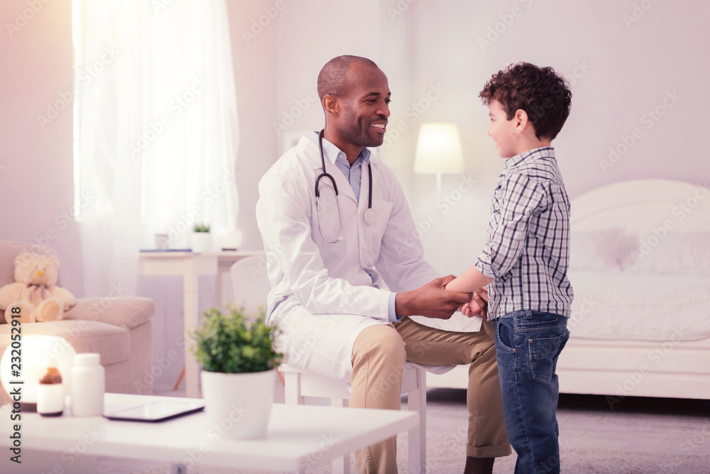 Fototapeta premium Joyful friendly doctor holding his patients hand