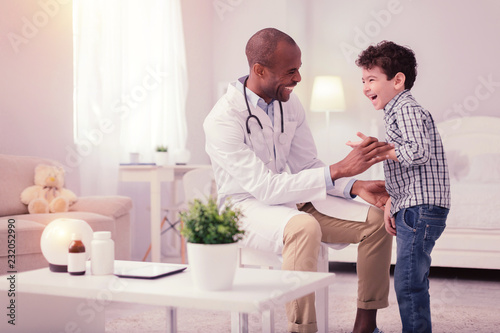 Happy positive boy standing near his doctor photo