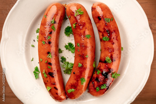 An overhead closeup photo of fried sausages, shot from the top on a white plate photo