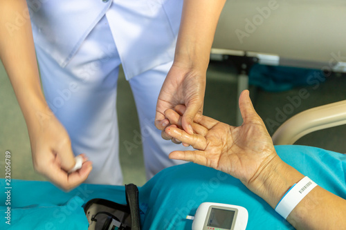 Nurse checking blood sugar level patoent with glucometer in hospital.