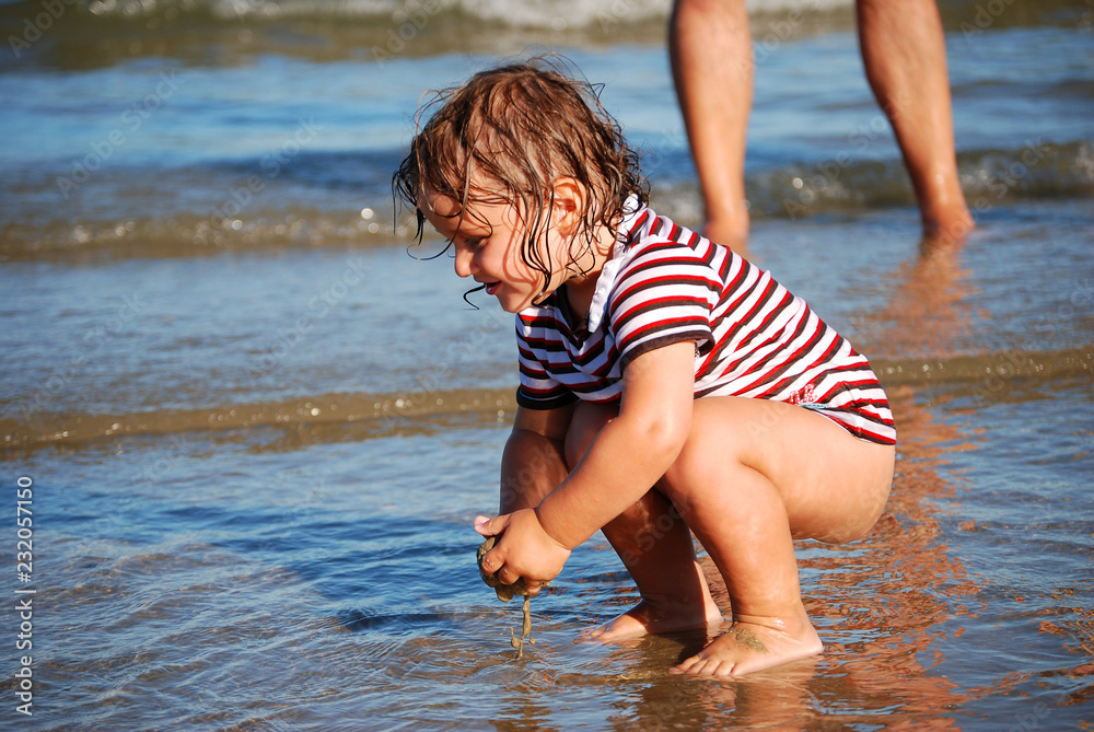 Kleinkind spielt im seichten Wasser am Strand Kleinkind spielt im seichten Wasser am Strand