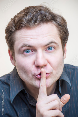 Man touching his lips with raised index finger showing quiet sign