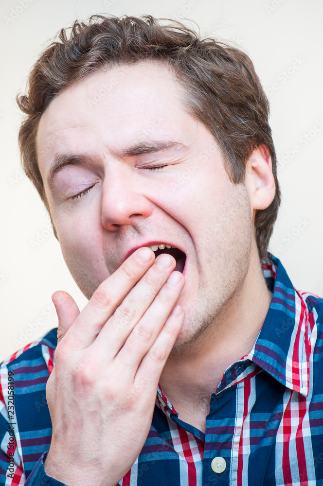 Yawning man covers his open mouth with fingers Yawning man covers his open mouth with fingers