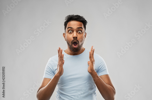emotion, expression and people concept - scared man in t-shirt over grey background