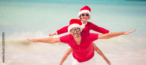 Father and daughter in Santa Hat have fun at tropical beach