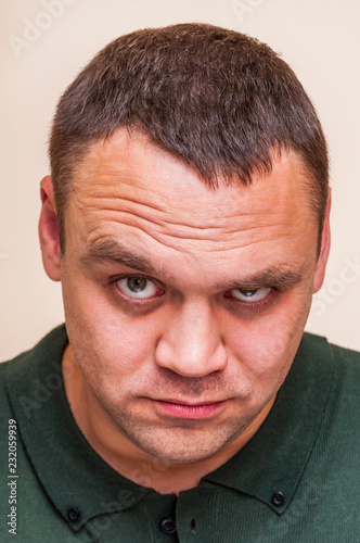 Young man questionably, mistrustfully looking with raised eyebrow photo