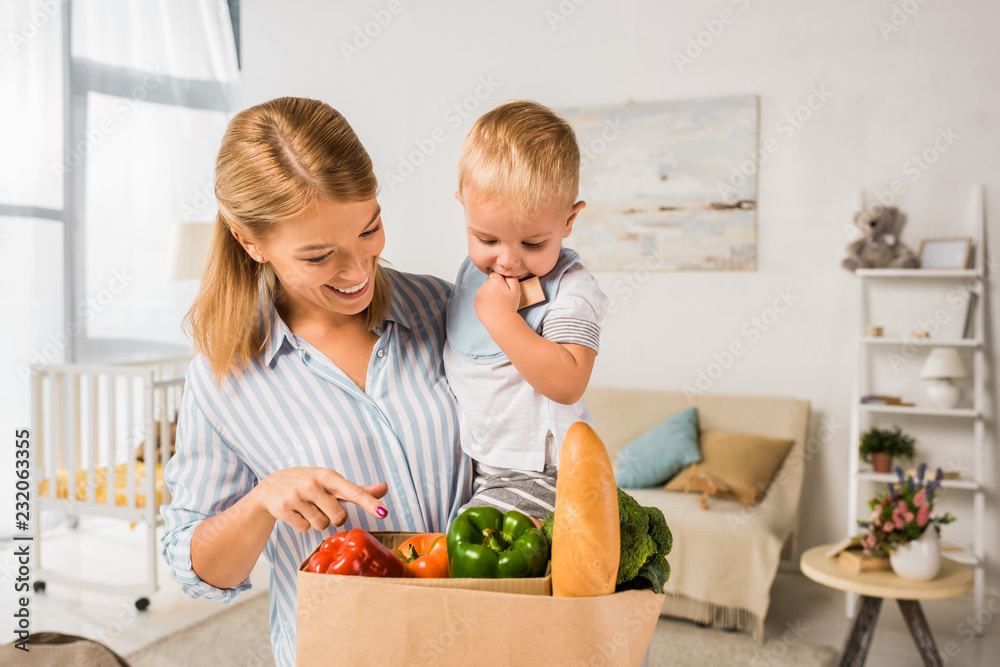 smiling happy mother showing groceries to son