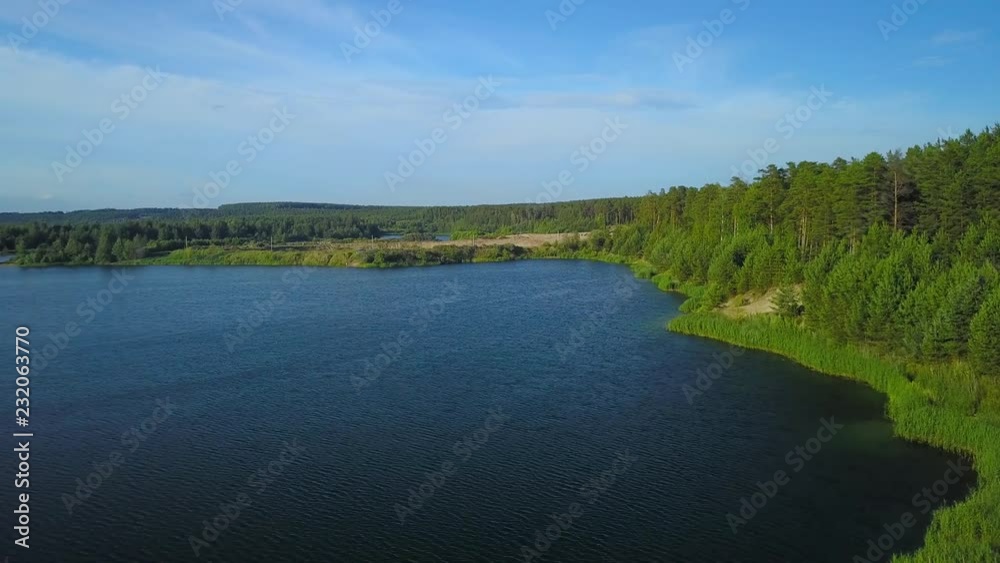 Flying over forest lake on Sunny summer day Flying over forest lake on Sunny summer day