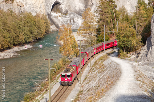 Passing by Glacier Express train in sunny autumnal Ruinaulta - Rheinschlucht (Rhine canyon) near Versam-Safien, Switzerland photo