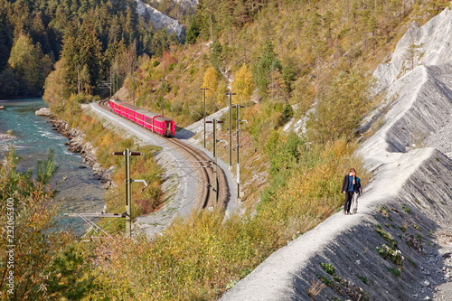 Tourists approaching Isla and observing passing by Glacier Express train in sunny autumnal Ruinaulta - Rheinschlucht (Rhine canyon), Valendas-Carrera, Switzerland photo