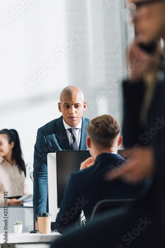 serious young african american businessman talking with colleague in office