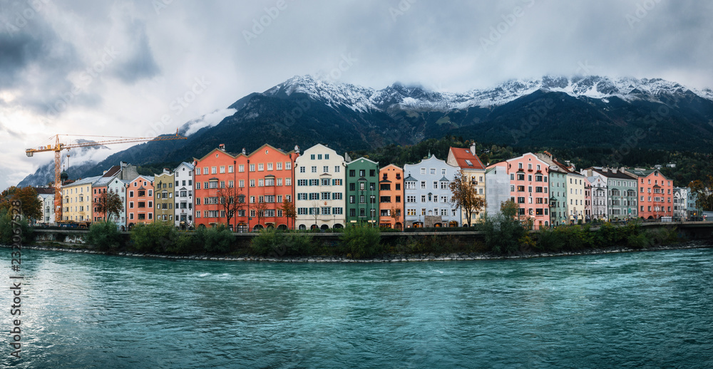 Panoramic view of Innsbruck with colorful houses along Inn river and famous Austrian snowy mountains in the background, Tyrol, Austria