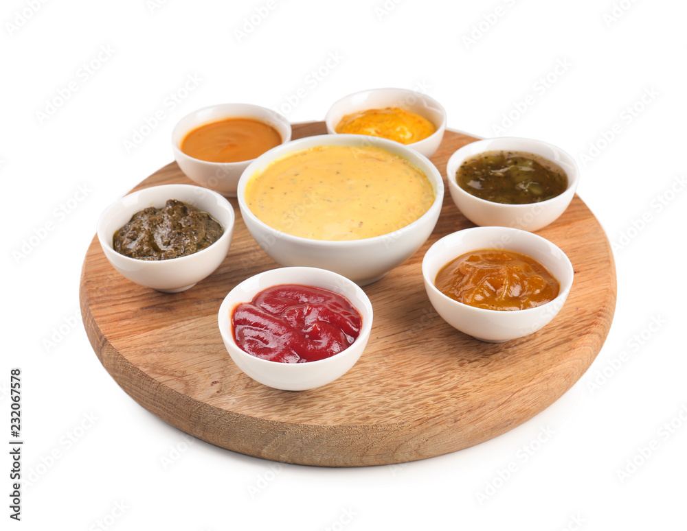 Wooden board with tasty sauces in bowls on white background