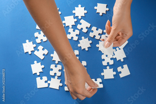 Woman doing jigsaw puzzle on color background © Pixel-Shot